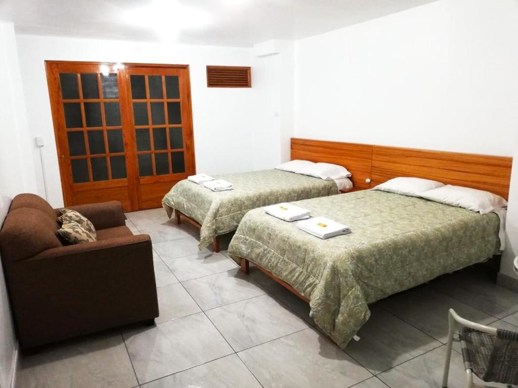 オクサパンパにあるExcelente ubicación! Bellas y cómodas habitaciones en el centro de Oxapampaのベッド2台とソファが備わるホテルルームです。