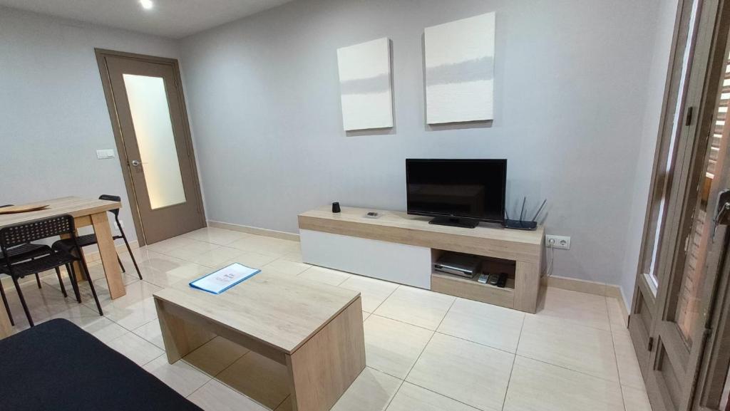 ein Wohnzimmer mit einem TV und einem Tisch in der Unterkunft Apartments Cal Benet in Camarasa