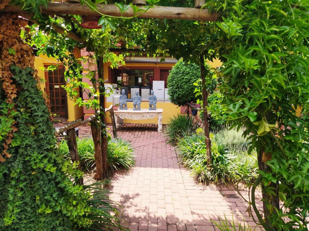 a garden with a patio with chairs and trees at Acre of Africa Guesthouse in Boksburg
