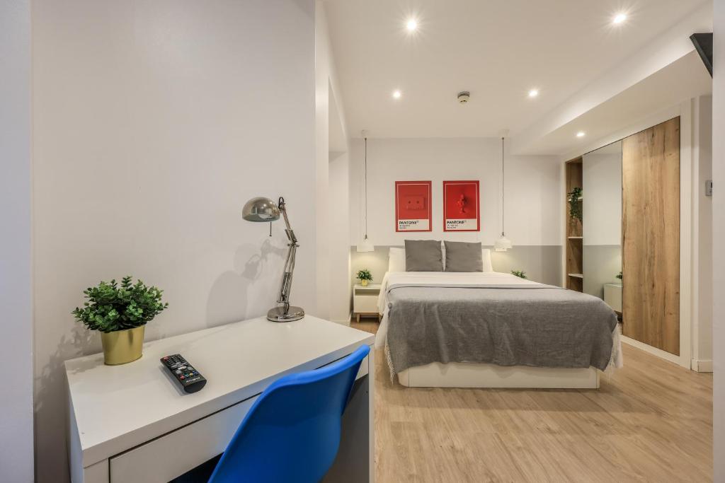 1 dormitorio con 1 cama, escritorio y sillas azules en AmazINN Places Blasco de Garay 113, en Madrid