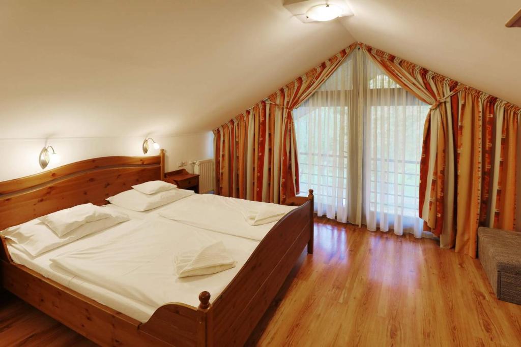 1 dormitorio con cama grande y ventana grande en Arany Szarvas Fogadó és Captain Drakes Pub, en Győr