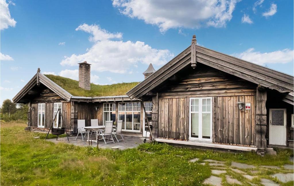 a wooden cabin with a table and chairs in front of it at Beautiful Home In stby With Wifi And 5 Bedrooms in Østby
