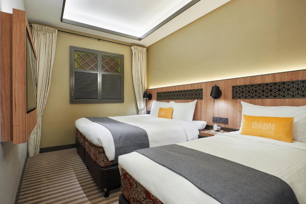 Una habitación de hotel con dos camas y una ventana. en Dash Living Rochor, en Singapur