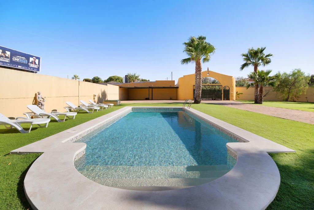 a swimming pool in a yard with chairs and a building at Villa Juani in Chiclana de la Frontera
