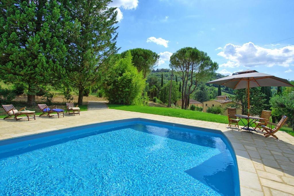 uma piscina com cadeiras e um guarda-sol em La Pimpinella di Semifonte em San Donnino