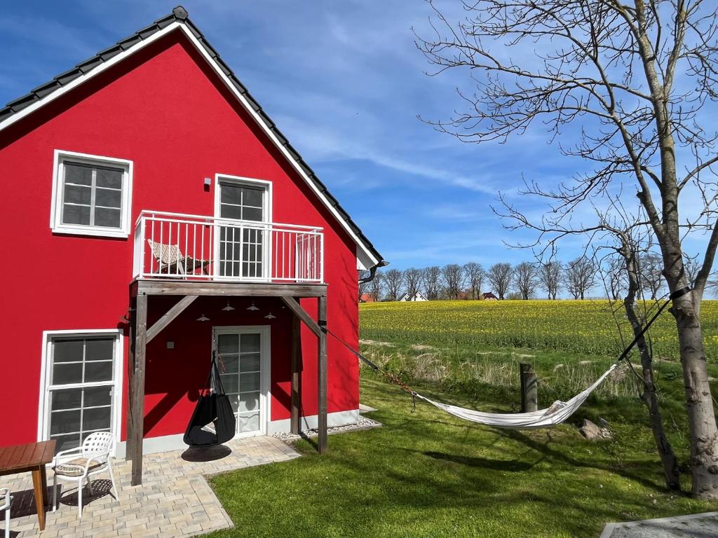 a red house with a hammock next to a field at Ostseehaus Boje in Krummin
