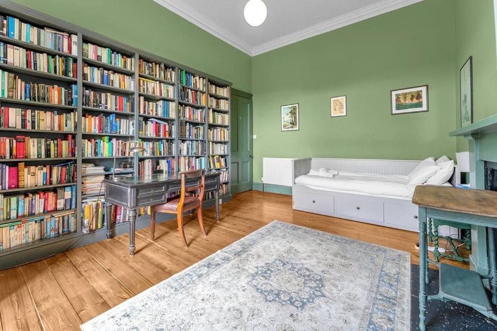 una biblioteca con una cama y estanterías llenas de libros en Bright and spacious flat overlooking the Meadows en Edimburgo