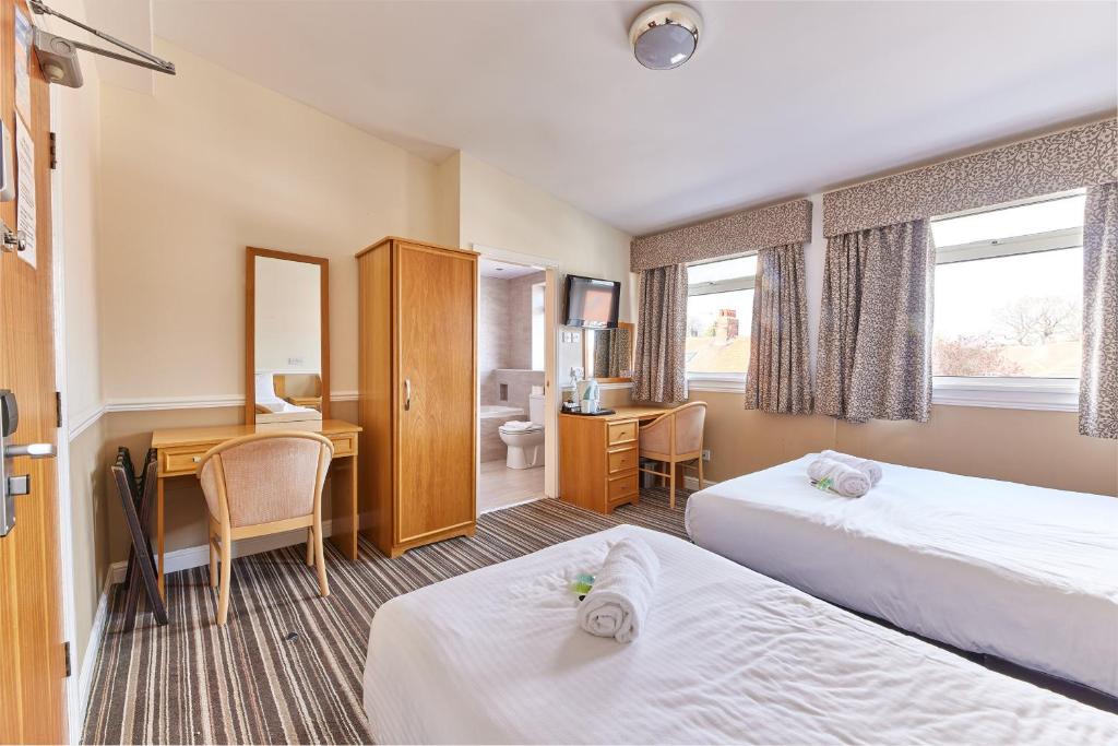 Cette chambre comprend deux lits et un bureau. dans l'établissement Properties Unique Dene Rooms Twin, à Newcastle upon Tyne