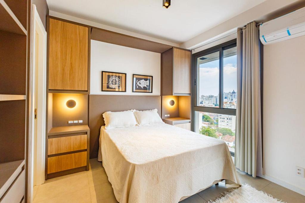 a bedroom with a bed and a large window at Apto com incrivel localizacao em Porto Alegre SP in Porto Alegre
