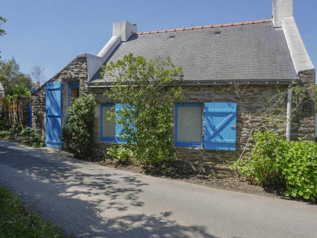 una casa de piedra con persianas azules en una calle en Maison Locmaria, 2 pièces, 4 personnes - FR-1-418-135 en Locmaria