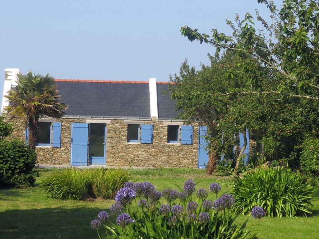 een stenen huis met blauwe ramen en bloemen in een tuin bij Maison Le Palais, 2 pièces, 3 personnes - FR-1-418-88 in Le Palais