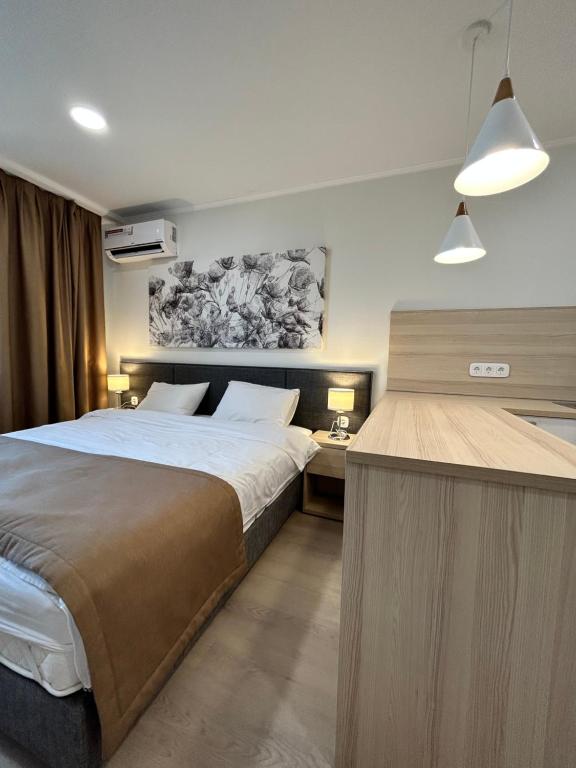 a bedroom with a large bed and a desk at Apart Astana in Taldykolʼ