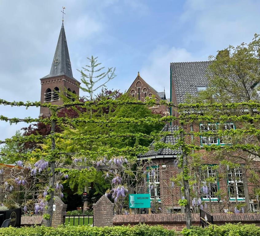 a building with a tower and a church with a steeple at B&B de wetenschap (der gastvrijheid) 