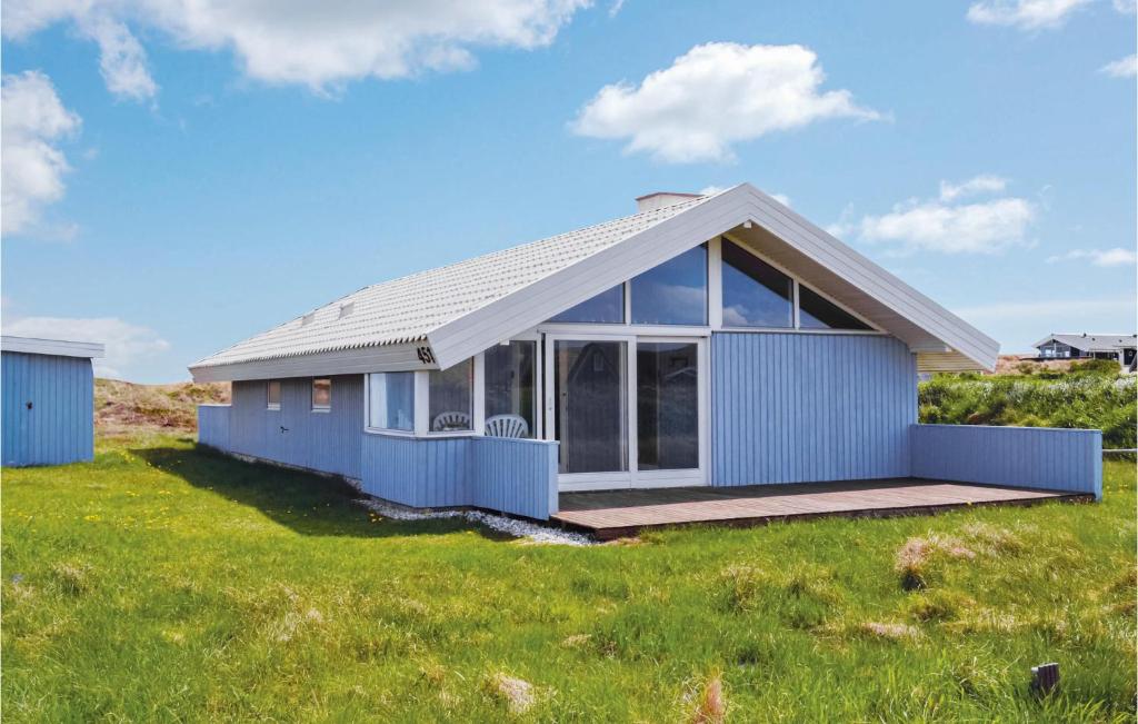 ein blaues Haus auf einem Grasfeld in der Unterkunft Nice Home In Hvide Sande With 3 Bedrooms, Sauna And Wifi in Hvide Sande