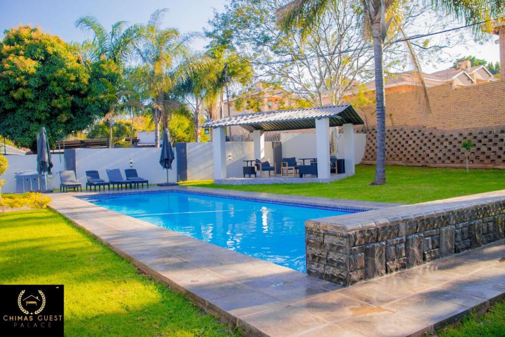 a swimming pool in a yard with a gazebo at Chimas Guest House in Musina