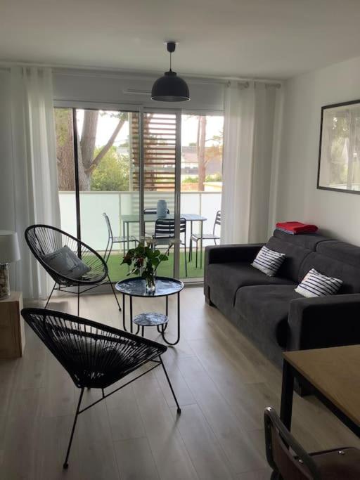 un salon avec un canapé, des chaises et une table dans l'établissement Carnac grand appartement cosy 2 personnes, à Carnac