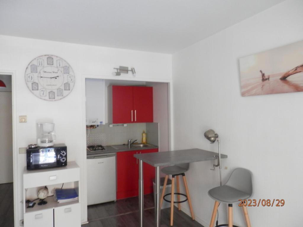 une cuisine avec des placards rouges et une table avec des tabourets dans l'établissement Arcachon centre 300m plage 50m gare SNCF, à Arcachon