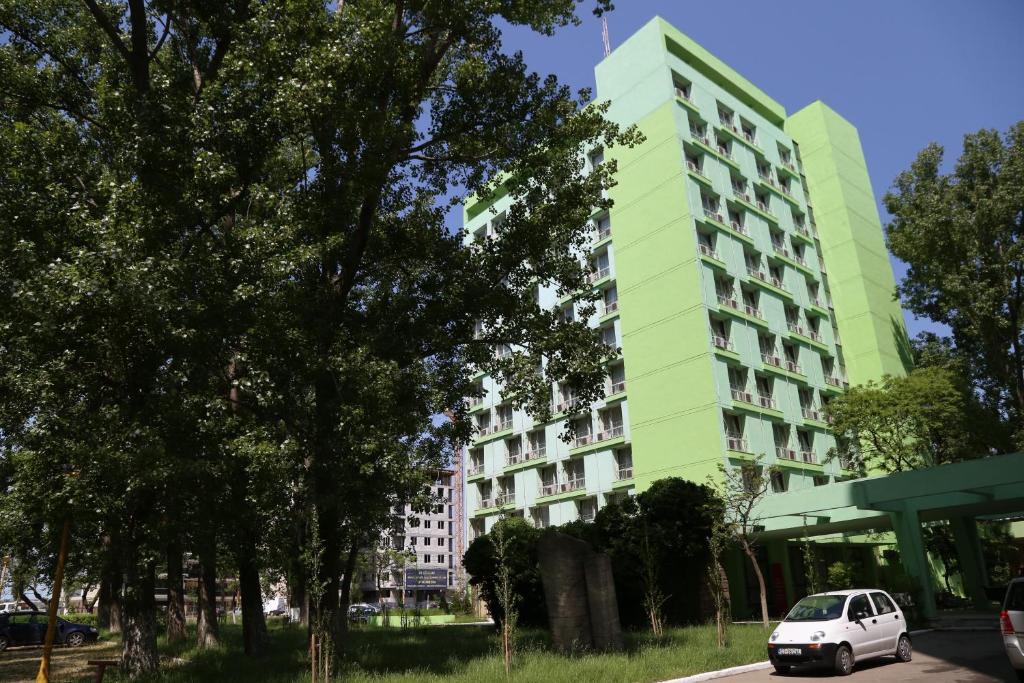 ein weißes Auto, das vor einem grünen Gebäude parkt in der Unterkunft Hotel National in Mamaia