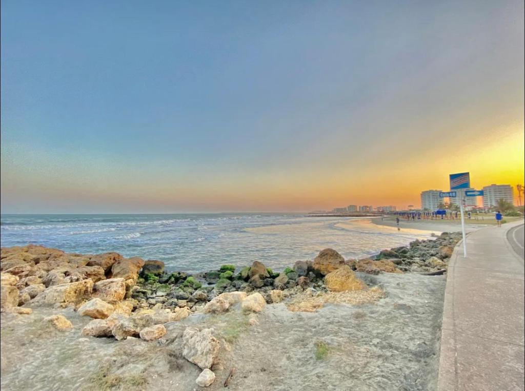 einen Strand mit Felsen, Meer und Gebäuden in der Unterkunft Lujoso apartamento frente a la playa in Cartagena de Indias