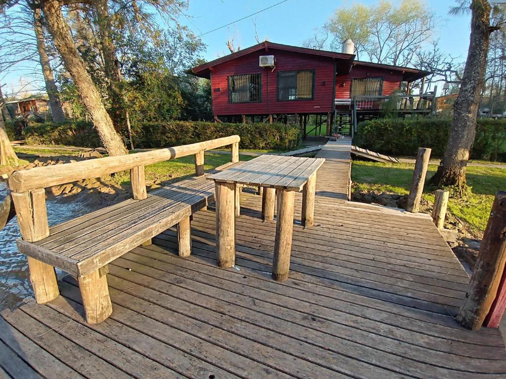 un banco de madera sentado en una terraza de madera frente a una casa en Casa isleña Extasis Propio en Tigre
