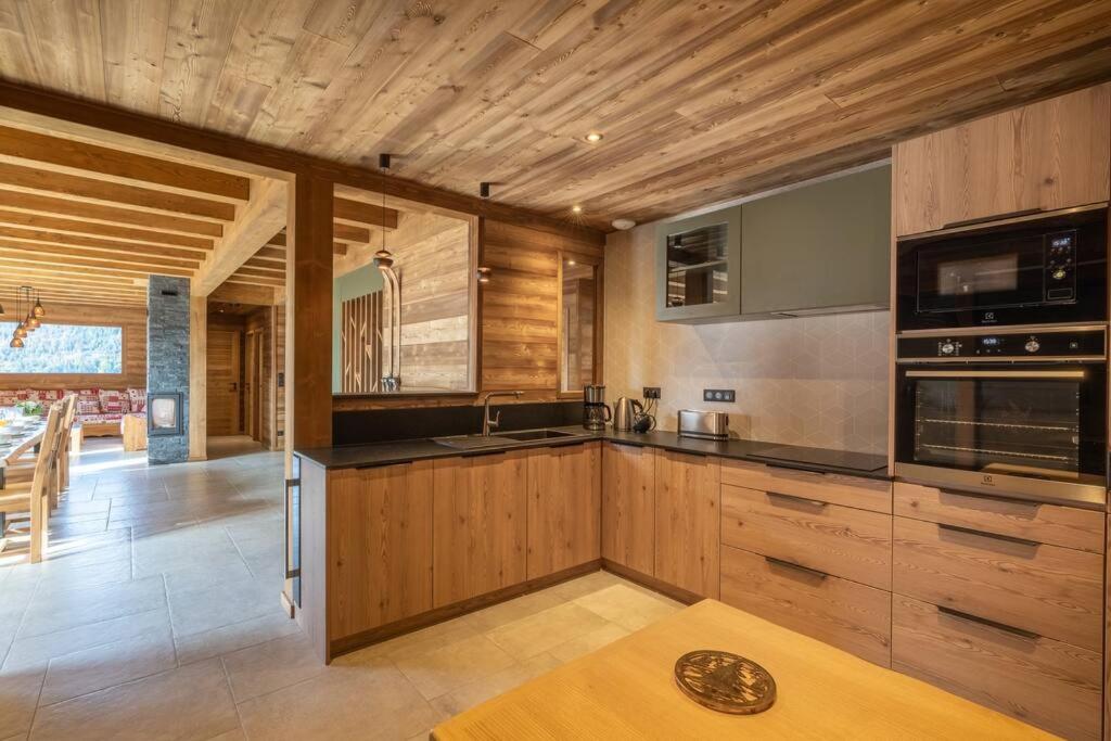 a kitchen with wooden cabinets and stainless steel appliances at Chalet La Tribu du Danay, neuf, 12 personnes in Saint-Jean-de-Sixt