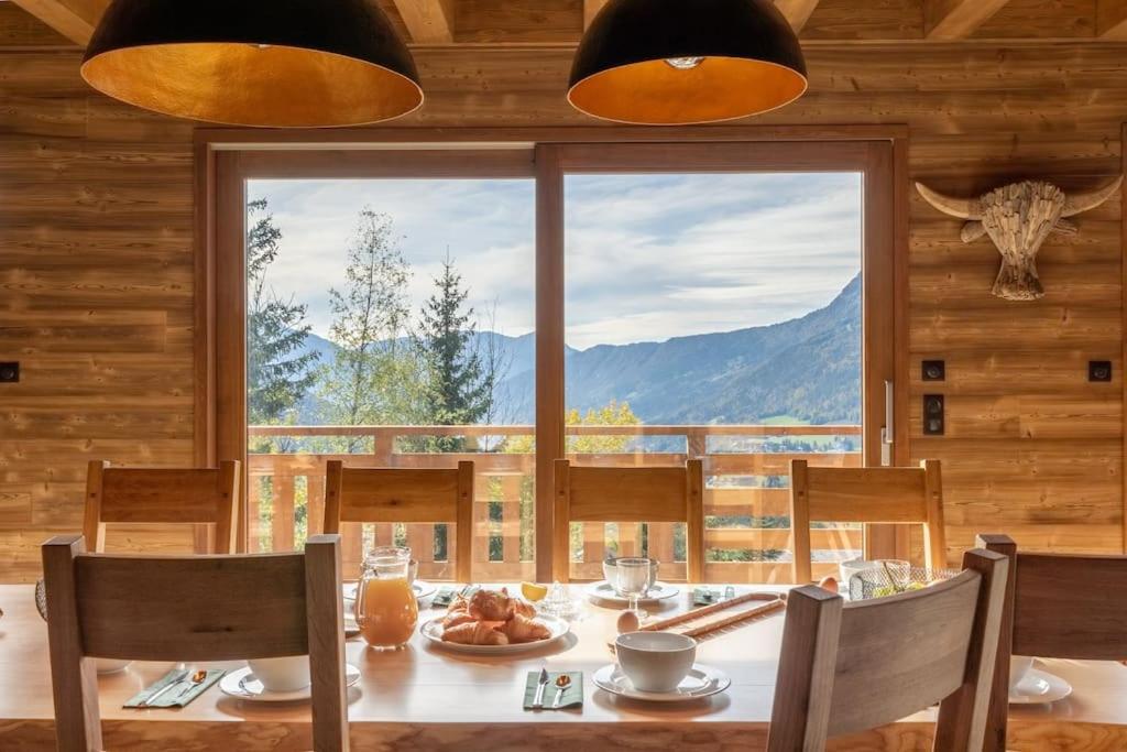 a dining room with a table and a large window at Chalet La Tribu du Danay, neuf, 12 personnes in Saint-Jean-de-Sixt