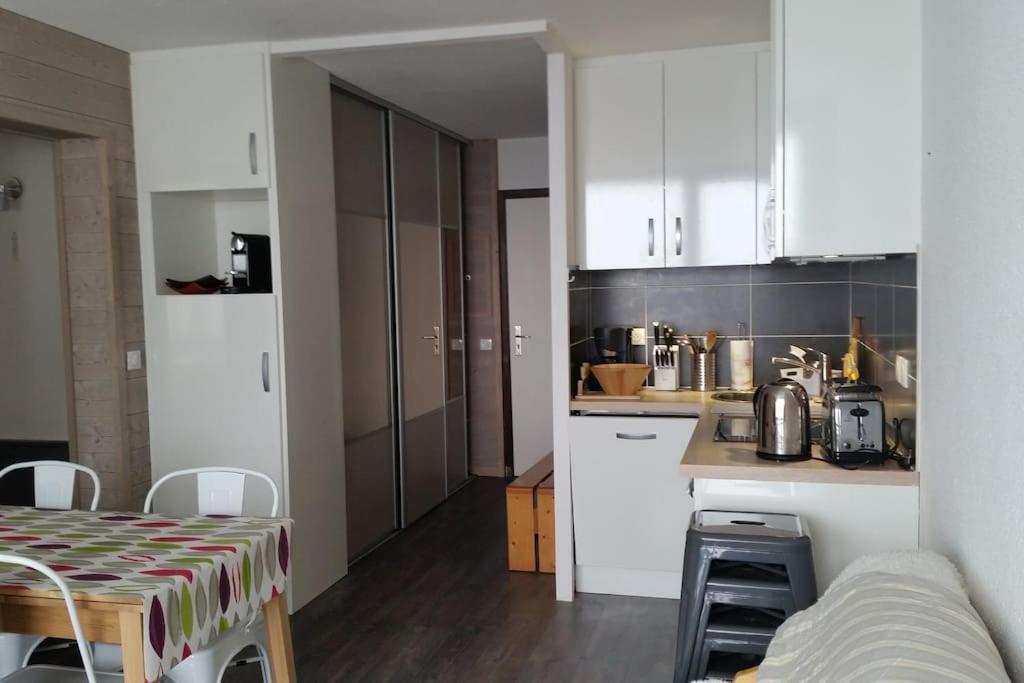 une cuisine avec des armoires blanches et une table dans une pièce dans l'établissement Paradiski calme et ensoleillé plan peisey, à Peisey-Nancroix