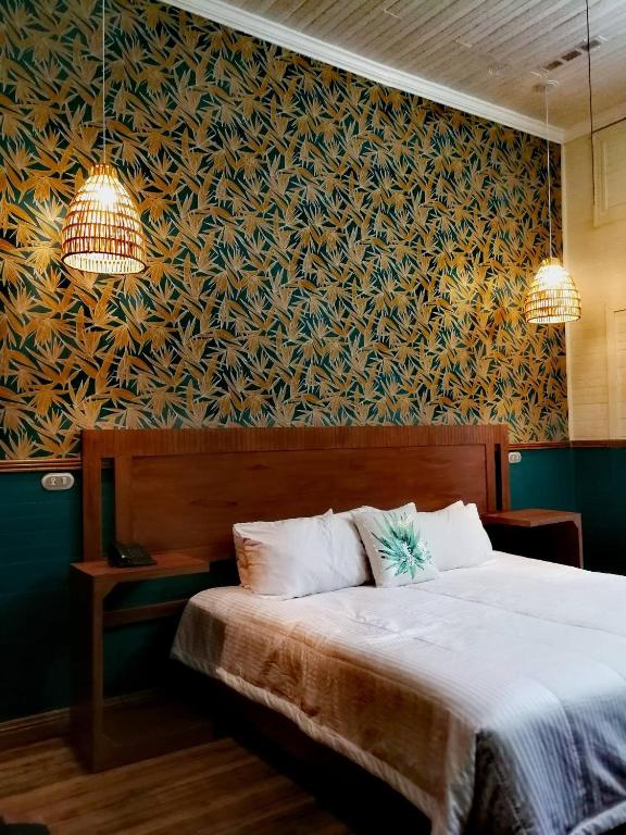 a bedroom with a bed and a wall with a floral wallpaper at Hotel Aranjuez in San José