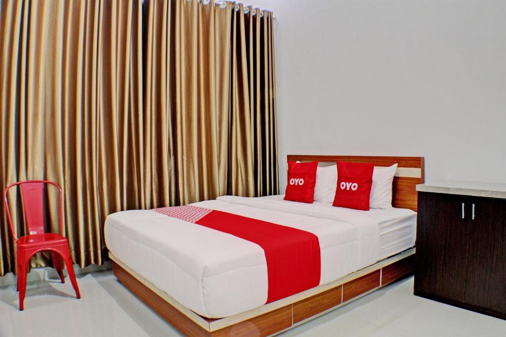 1 dormitorio con cama con almohadas rojas y silla roja en OYO 92945 Guest House Nusa Indah Syariah, en Bandar Lampung