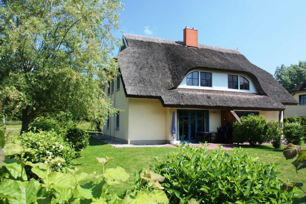 uma casa com telhado de palha e um quintal em Komfortables Reetdachferienhaus Hasel 1 em Puddemin