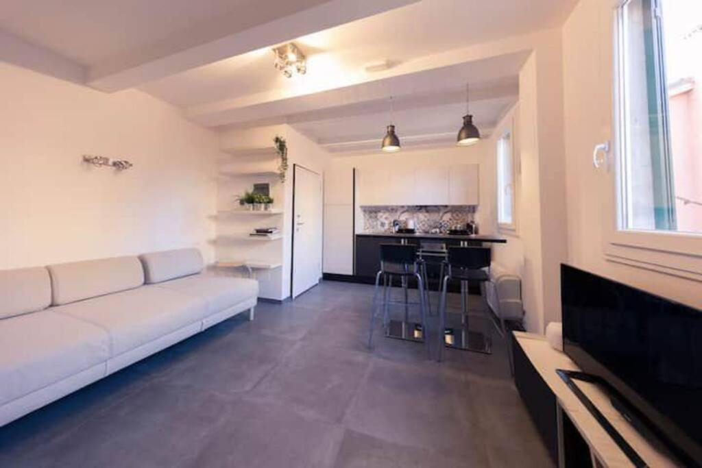 a living room with a white couch and a kitchen at CA’ De La Torre in Bologna