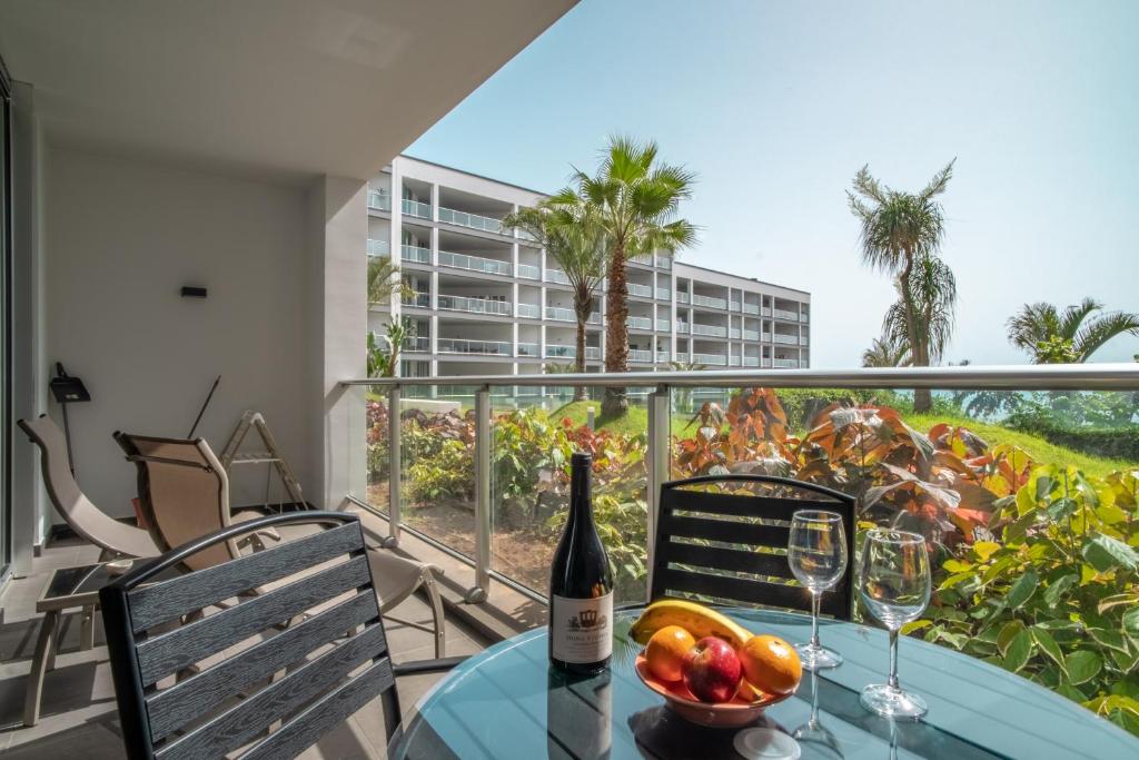 uma mesa com uma garrafa de vinho e fruta numa varanda em Madeira Residence Apartment AK5 em Funchal