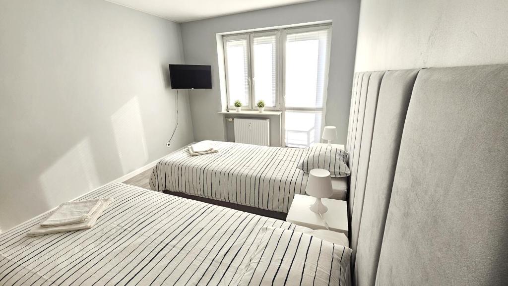 a white bedroom with two beds and a window at Pięćdziesiątka in Płock