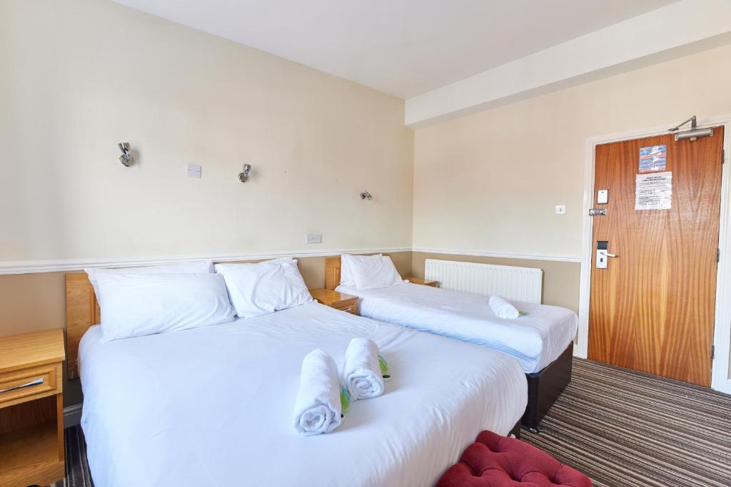 two beds in a hotel room with towels on them at Properties Unique Dene Rooms - Family Room in Newcastle upon Tyne