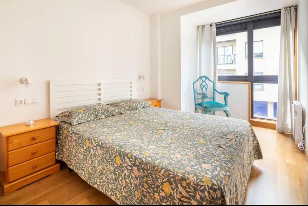 a bedroom with a bed and a chair and a window at Apartamento Centro de Baiona con Parking in Baiona
