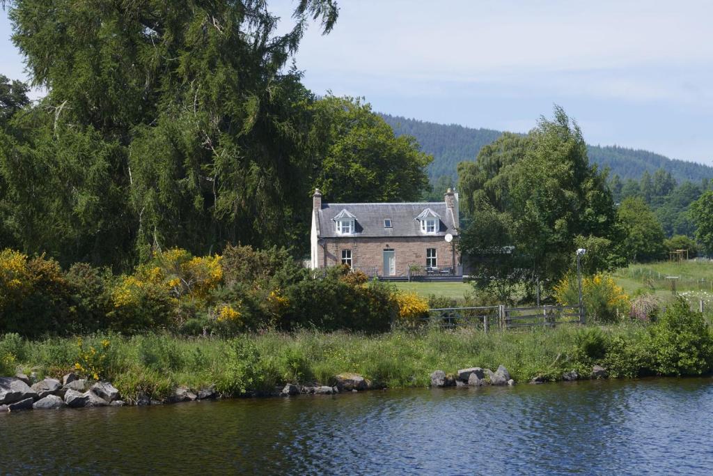 a house sitting on the side of a river at Dunaincroy Farmhouse in Inverness