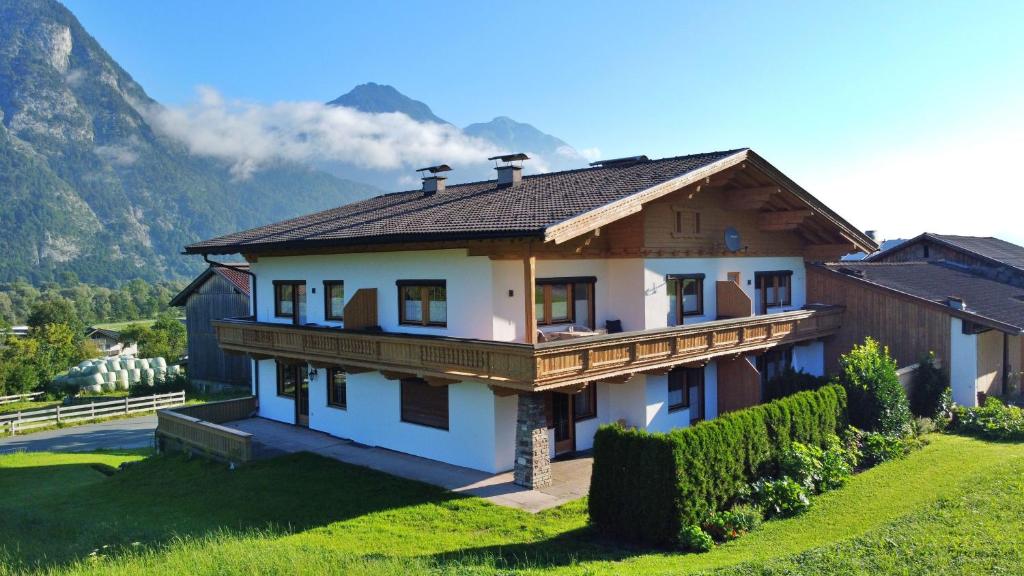 a house on a hill with mountains in the background at Bucherwirt Appartements in Buch bei Jenbach