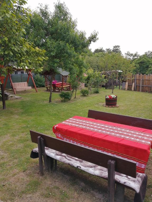 a bench with a red blanket on it in a park at Őrségi Lápréti Vendégház in Szőce