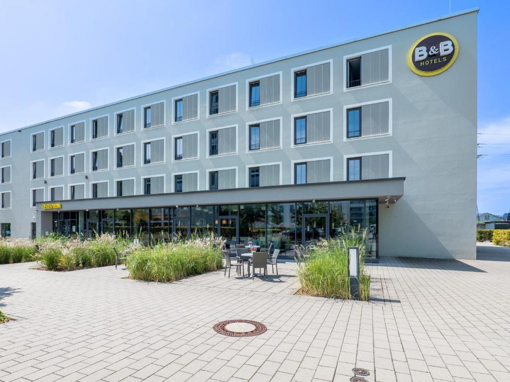 a building with tables and chairs in front of it at B&B Hotel Offenburg in Offenburg