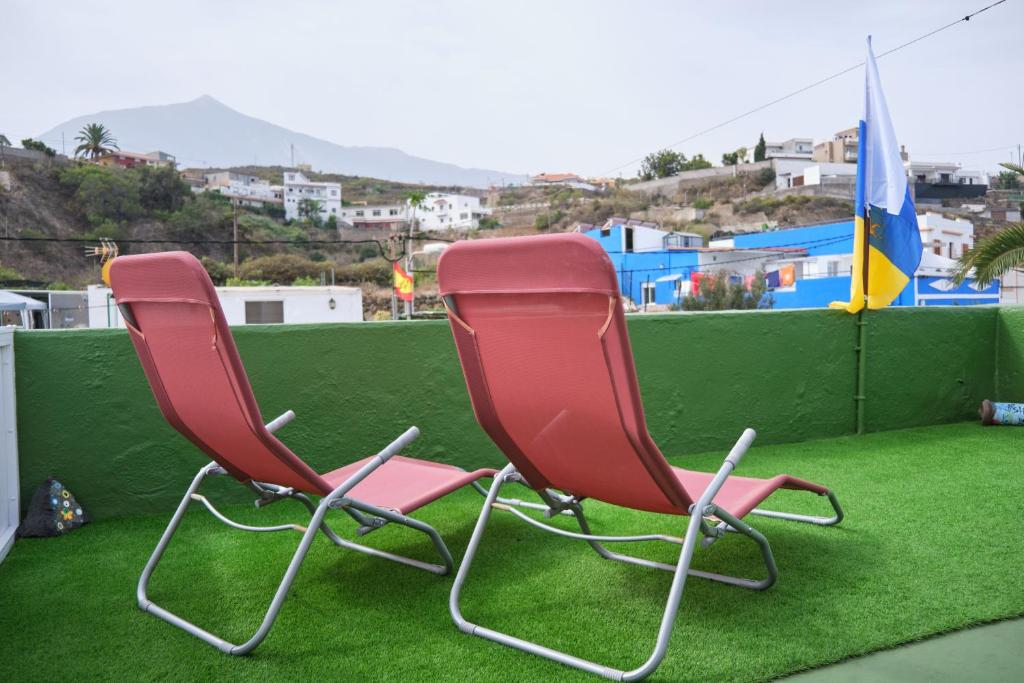 La GuanchaにあるCuarto Verode Apartamento Santo Domingoの緑の芝生の上に座る赤い椅子2脚