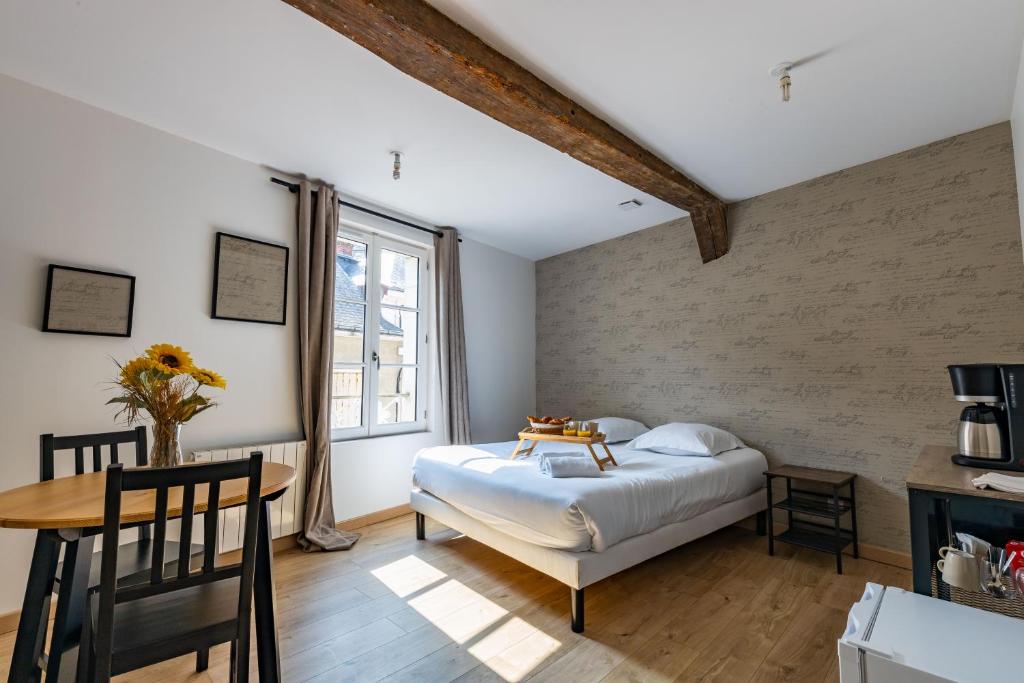 a bedroom with a bed and a table and a window at La Suite Littéraire, 5mn du ZooParc de Beauval in Saint-Aignan