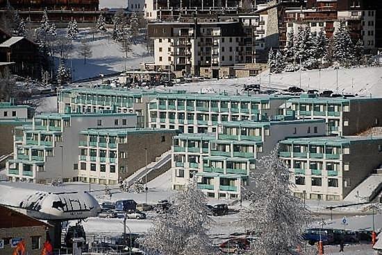 een groep gebouwen met sneeuw op de grond bij villaggio olimpico in Sestriere