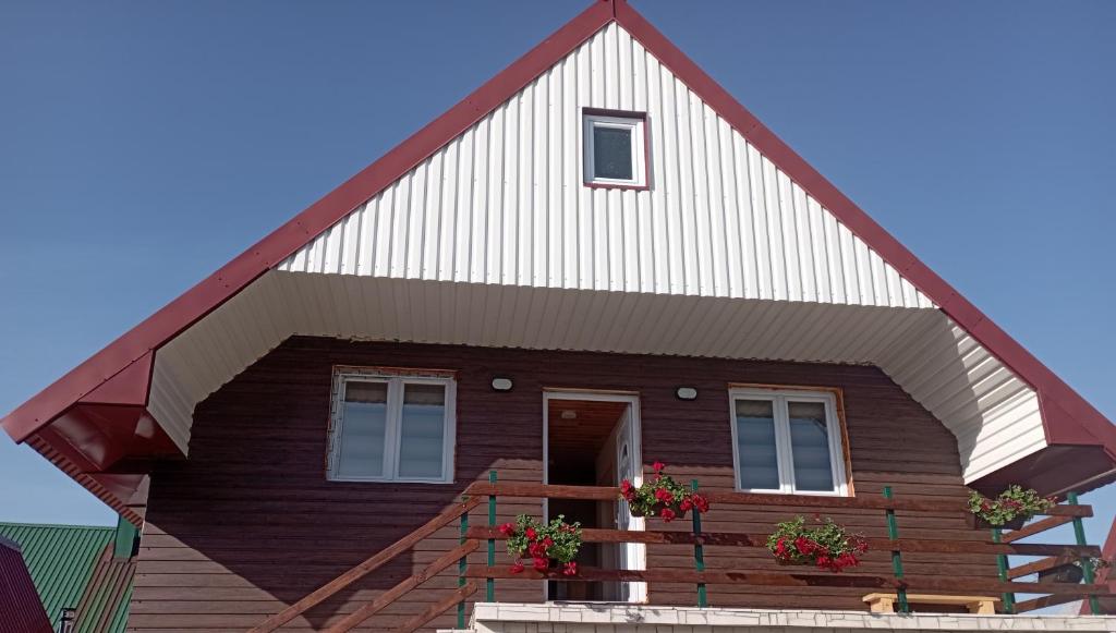 una pequeña casa con un gran techo de gambrel en Apartman JOVANA, en Žabljak