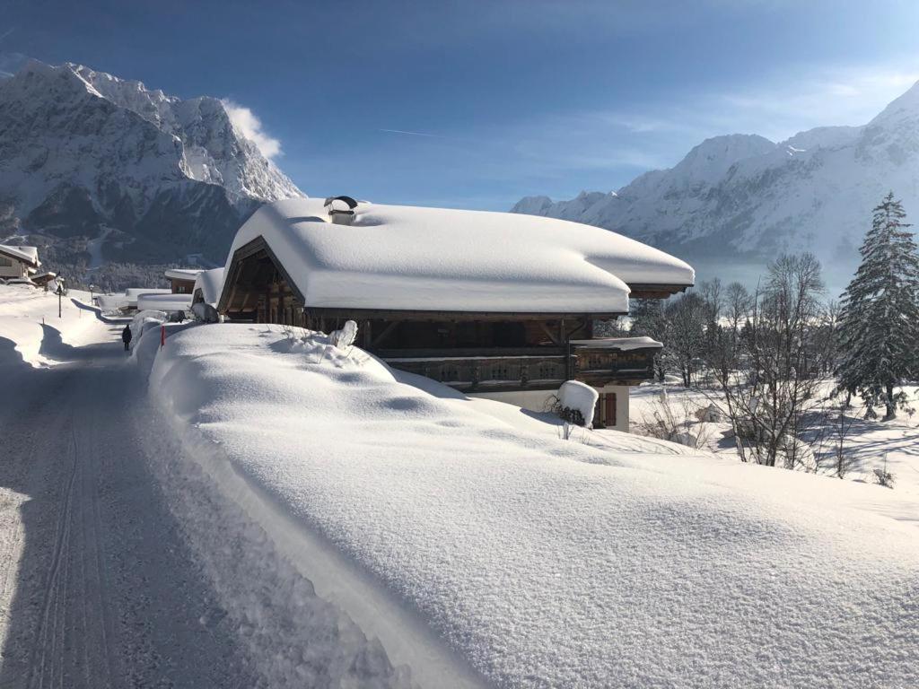 a building covered in snow next to a road at Zugspitzchalet in Lermoos