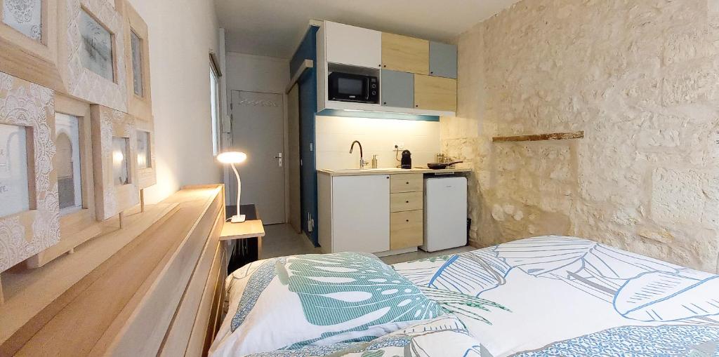 mały pokój z łóżkiem i kuchnią w obiekcie Studio sur chemin de Compostelle w mieście Port-de-Piles
