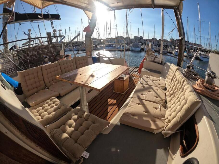 a boat with a table and couches on the deck at Voilier traditionnel, tout confort et au calme in Gruissan