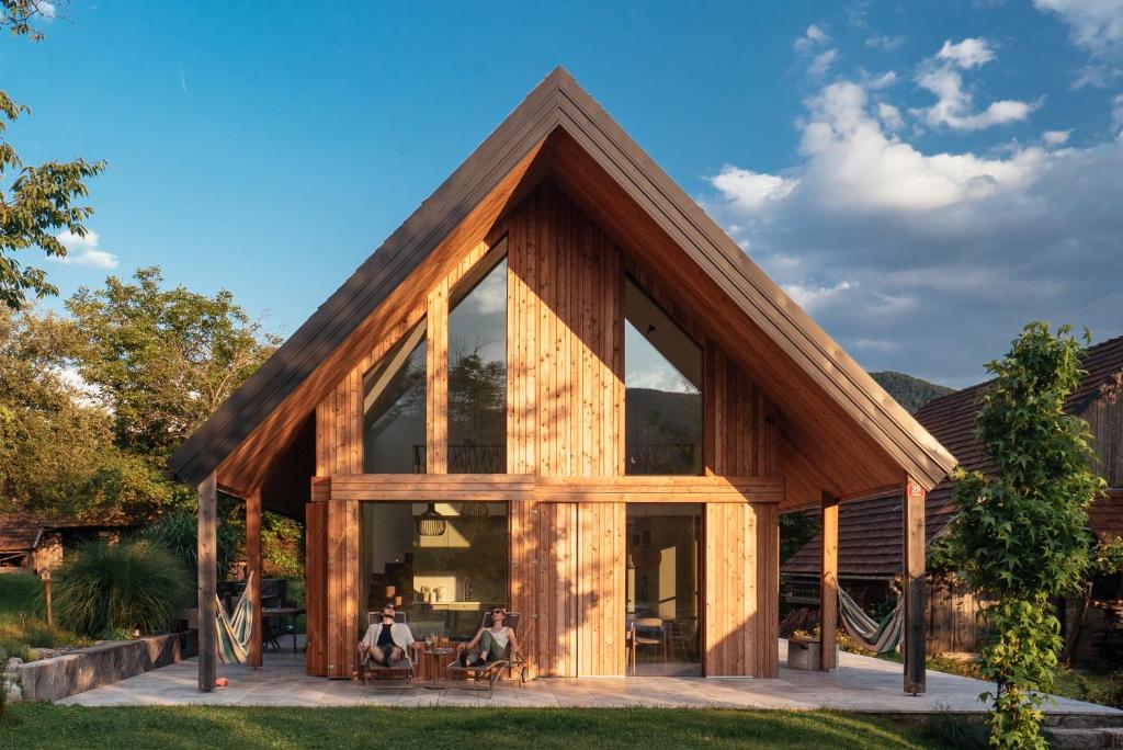 ein Holzhaus mit großen Fenstern und zwei Personen sitzen in der Unterkunft Holiday House BALE, BALE in Kostel