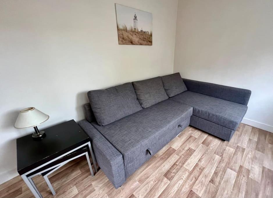 a gray couch in a living room with a table at Seaside Tiny House only 300 meters from the beach in Noordwijk