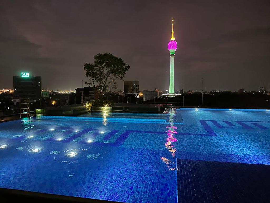 a swimming pool at night with a tv tower in the background at Cosy home in heart of Colombo at Capitol Twinpeaks. in Colombo