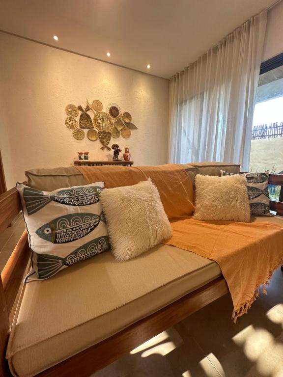 a couch with pillows on it in a living room at Casa Natture Patacho in Pôrto de Pedras